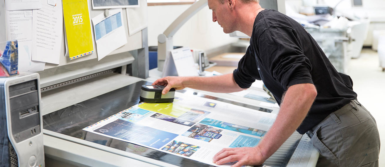 inside the cradle to cradle printing hall, printer checking a print on his desk